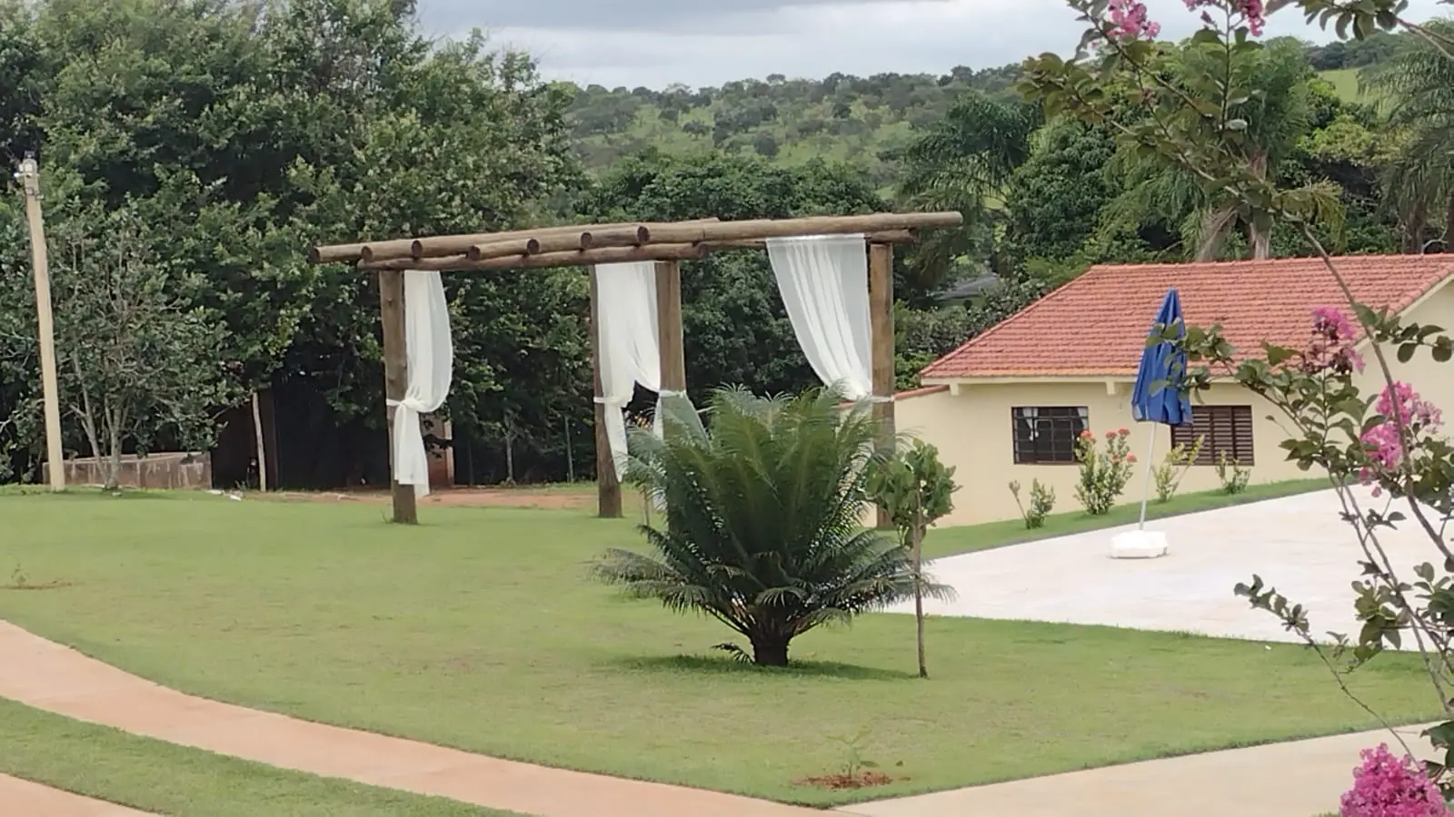 Gramado com pergolado de madeira e tecidos brancos para eventos